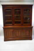 A Victorian style triple bookcase (French made), the upper section with arched glazed panels,