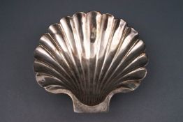 A 19th century French white metal shell shaped butter dish, on four ball feet,