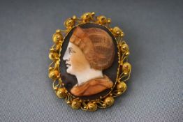 A carved onyx/shell cameo brooch with intricate yellow gold mount testing as 22ct gold Pin and