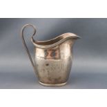 A silver oval cream jug with a scroll handle, reeded borders an initials, Chester 1908,