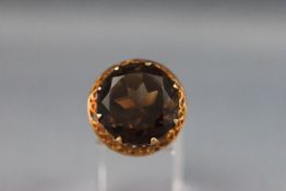 A yellow metal single stone ring set with a round smokey quartz. Stamped 9ct. Size: K 9.