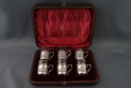 A set of six silver mounted liqueur glasses, each with scrtoll handles embossed with figures,