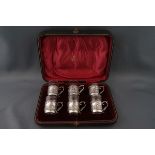 A set of six silver mounted liqueur glasses, each with scrtoll handles embossed with figures,