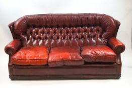 A red leather button back three seat sofa,