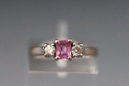 A white metal three stone ring set with pink sapphire and diamonds.