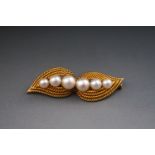 A yellow metal leaf brooch set with six graduated cultured pearls. Pin and barrel safety catch.