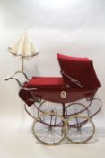 A Silver Cross babies pram with red livery and hood,
