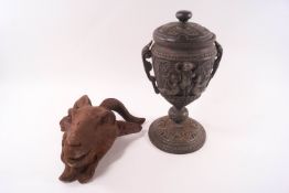 A cast iron ram's head urn mount, 21cm high, and an iron urn and cover with classical decoration,