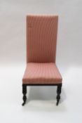 A Victorian mahogany nursing chair on turned front legs with pink striped uholstery