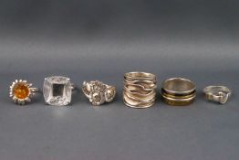 A group of six silver and white metal designer rings, including a Lalique glass ring,