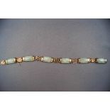 A jade linked bracelet interspaced with yellow metal pierced links of Chinese symbols.