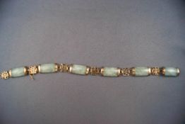 A jade linked bracelet interspaced with yellow metal pierced links of Chinese symbols.