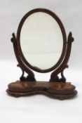 A Victorian oval mahogany swing frame dressing table mirror with twin lidded compartments,