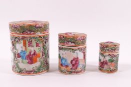 A Canton porcelain nest of three cylindrical boxes, decorated with figures and butterflies,