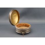 A silver round trinket box on three feet with a silk lined interior,