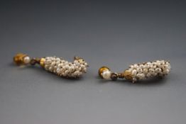 A yellow metal pair of drop earrings each wire set with a rice freshwater pearls.