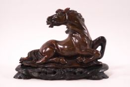 A Chinese carved soapstone figure of a kneeling horse with it's head turned round, 13cm wide,