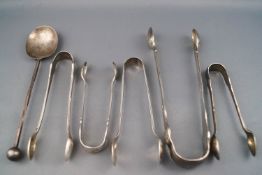 Five silver sugar tongs, George III and later, together with a silver spoon with ball finial,