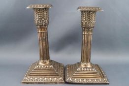 A pair of silver short square cluster-column candlesticks with stepped square bases and nozzels,