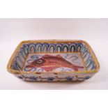 A Continental earthenware dish painted with a fish within a patterned border,