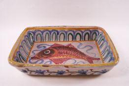 A Continental earthenware dish painted with a fish within a patterned border,