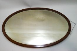 An early 20th century oval mahogany framed wall mirror,