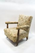 An early 20th century oak armchair on casters, with tapestry style upholstery,