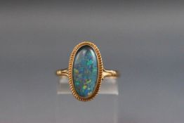 A yellow metal ring set with an oval cabchon opal triplet. Size P 2.