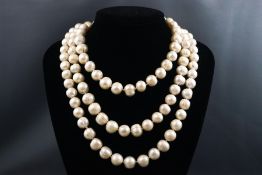 A three strand string of cultured freshwater baroque pearls with sterling silver emerald set push