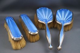 A silver and blue enamel four piece dressing table set comprising of a pair of hair brushes and a