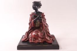 A Japanese painted bronze figure of a seated Geisha with her arms crossed, on a square stepped base,