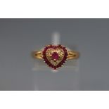 A yellow metal heart shape cluster ring set with rubies and diamonds.