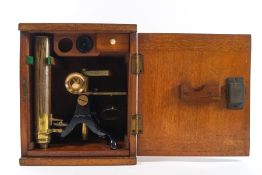 An early 20th century brass and lacquered microscope, with blanks slides and additional lens,