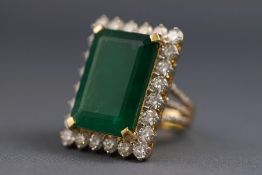A yellow and white metal cluster ring. Set with a rectangular cut emerald measuring 29.0mm x 15.