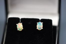A modern white metal pair of single stone stud earrings each set with an oval cabochon water opal