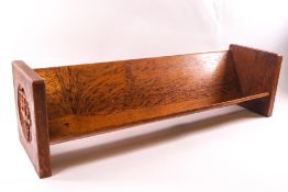 An Arts & Crafts oak bookstand, the ends carved with a coat of arms and the letters 'CHPS', 61.