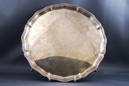 A silver salver with beaded border on three ball and claw feet, 24.