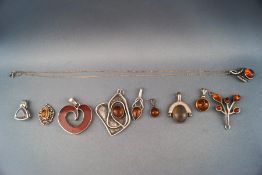 A selection of ten silver pendants consisting of mostly amber set abstract designs.