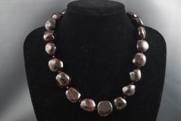 A single strand of large garnet polished beads with silver T-bar clasp.