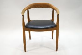 A 1960's Danish elm armchair with black leatherette seat, retailed by Eilerson,