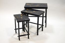 A Japanese lacquered nest of three tables, the tops depicting flying cranes and pagodas,