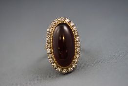 A yellow and white metal cabochon almandine garnet and diamond cluster ring.