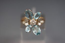 A yellow metal abstract cluster ring set with aquamarine and a central 4.