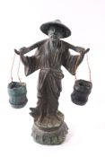 A Chinese bronze patinated figure of a peasant carrying buckets,