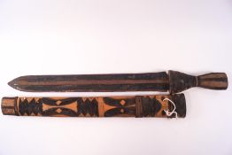 A Zimbabwe sword with wooden handle and sheath, carved and blackened linear patterns,