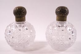A pair of Victorian cut glass scent bottles of spherical form with stoppers and plated tops,