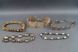 A selection of five silver bracelets consisting of a filigree panel bracelet, a gate bracelet,