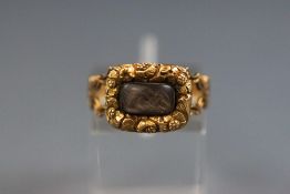 A Victorian yellow metal mourning ring with encased plaited human hair. Tests indicate 15ct gold.