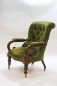 A Victorian mahogany button back armchair with scroll arms on turned front legs and casters,