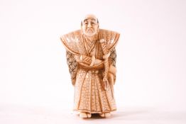 An early 20th century carved and part stained ivory netsuke, of a frowning warrior,
